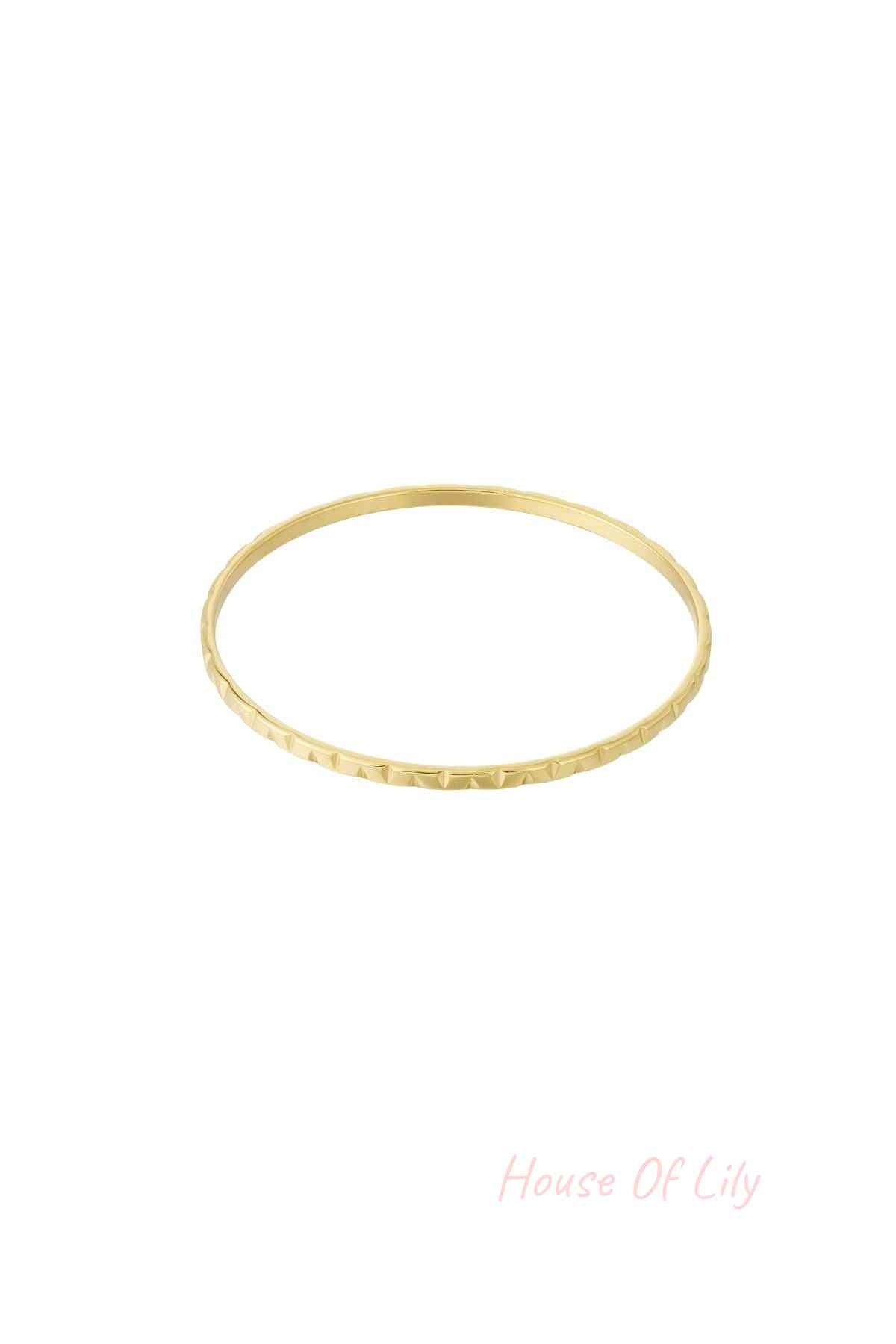 Gold textured bangle with subtle geometric pattern on white background
