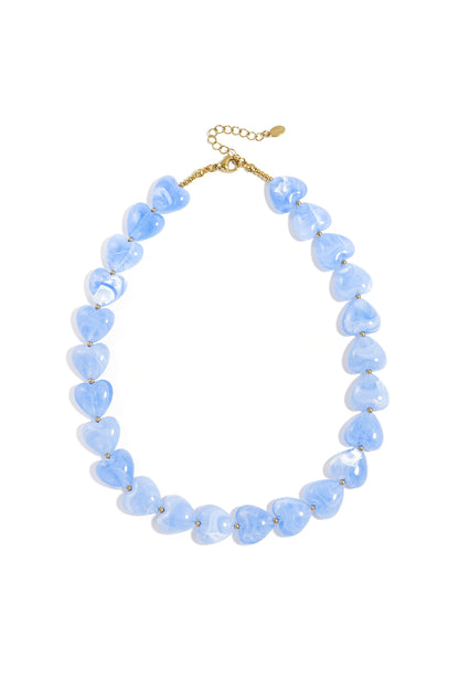 Baby blue heart-shaped acrylic bead necklace with gold spacers on white background