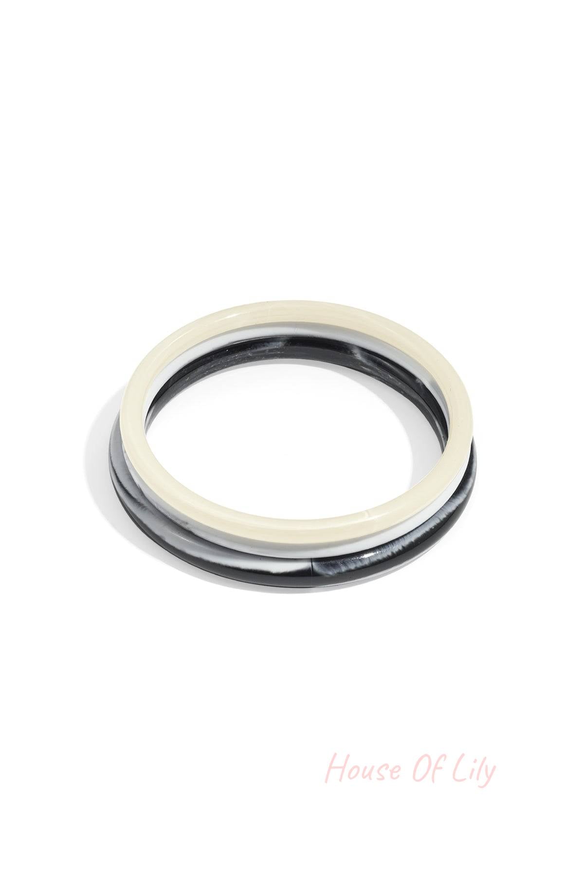Set of two resin bangle bracelets in solid cream and marbled black and white, featuring a smooth, minimalist design.