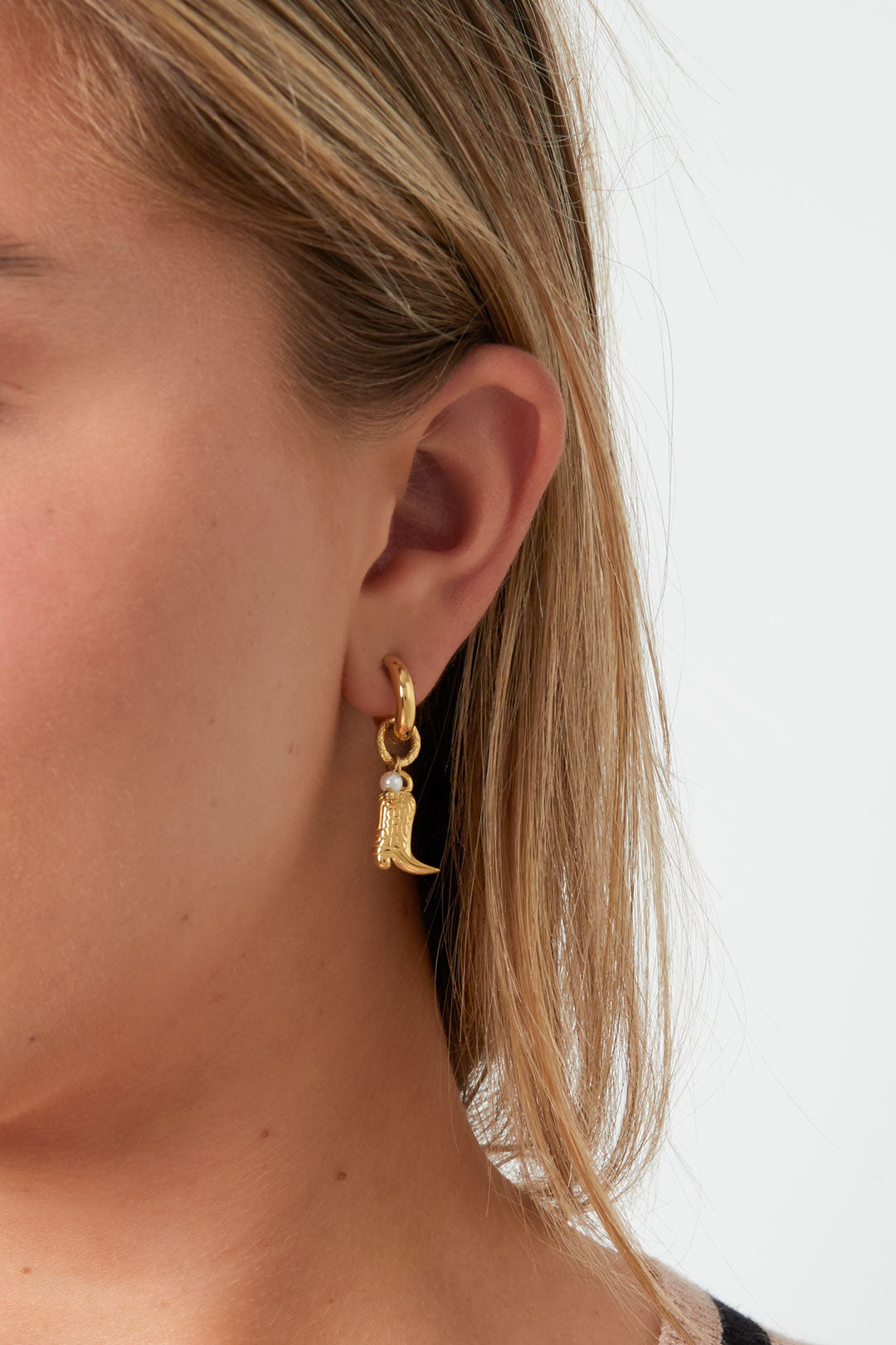 Model wearing gold cowboy boot charm hoop earring showing size and style