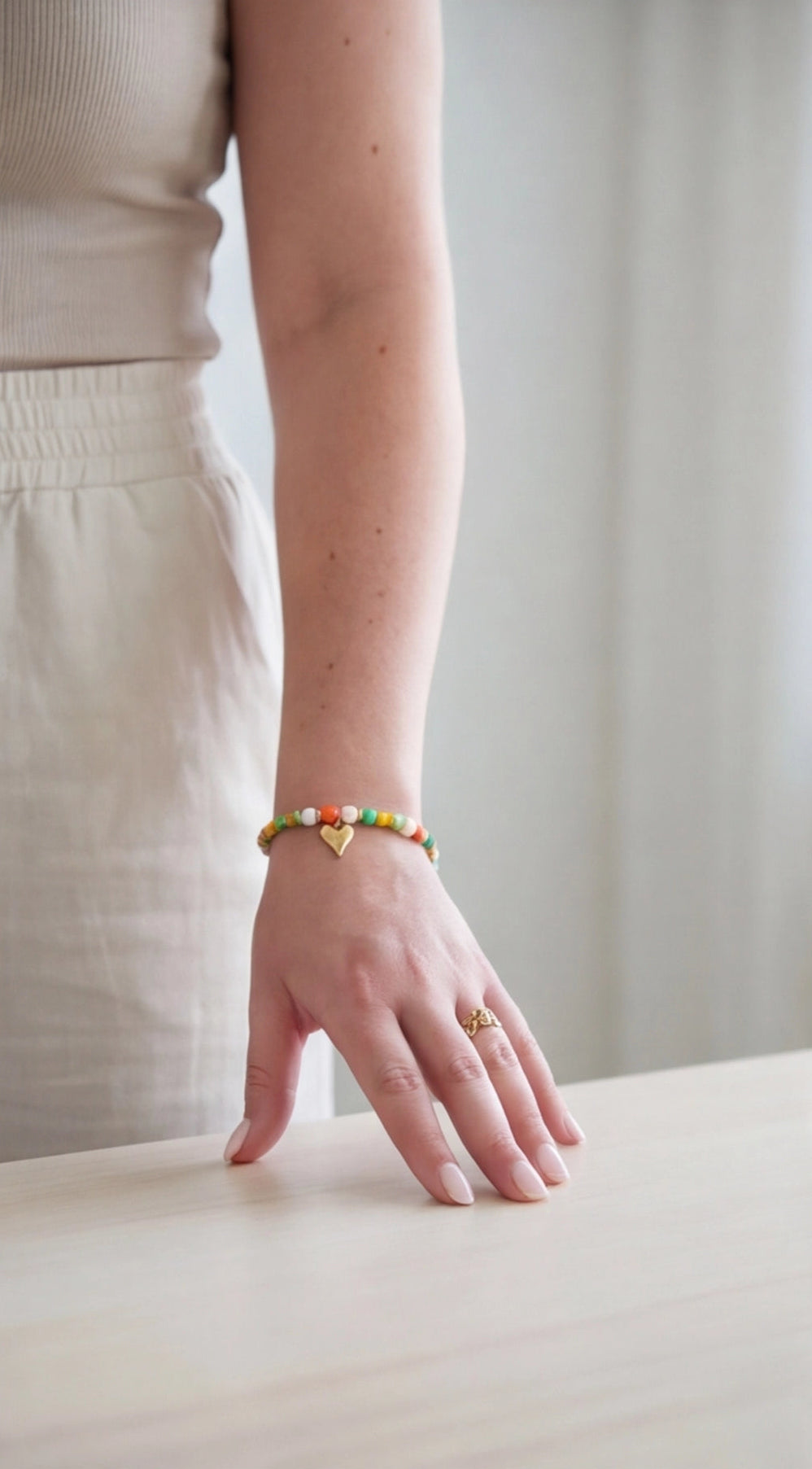 Person wearing a colorful bracelet on a plain background