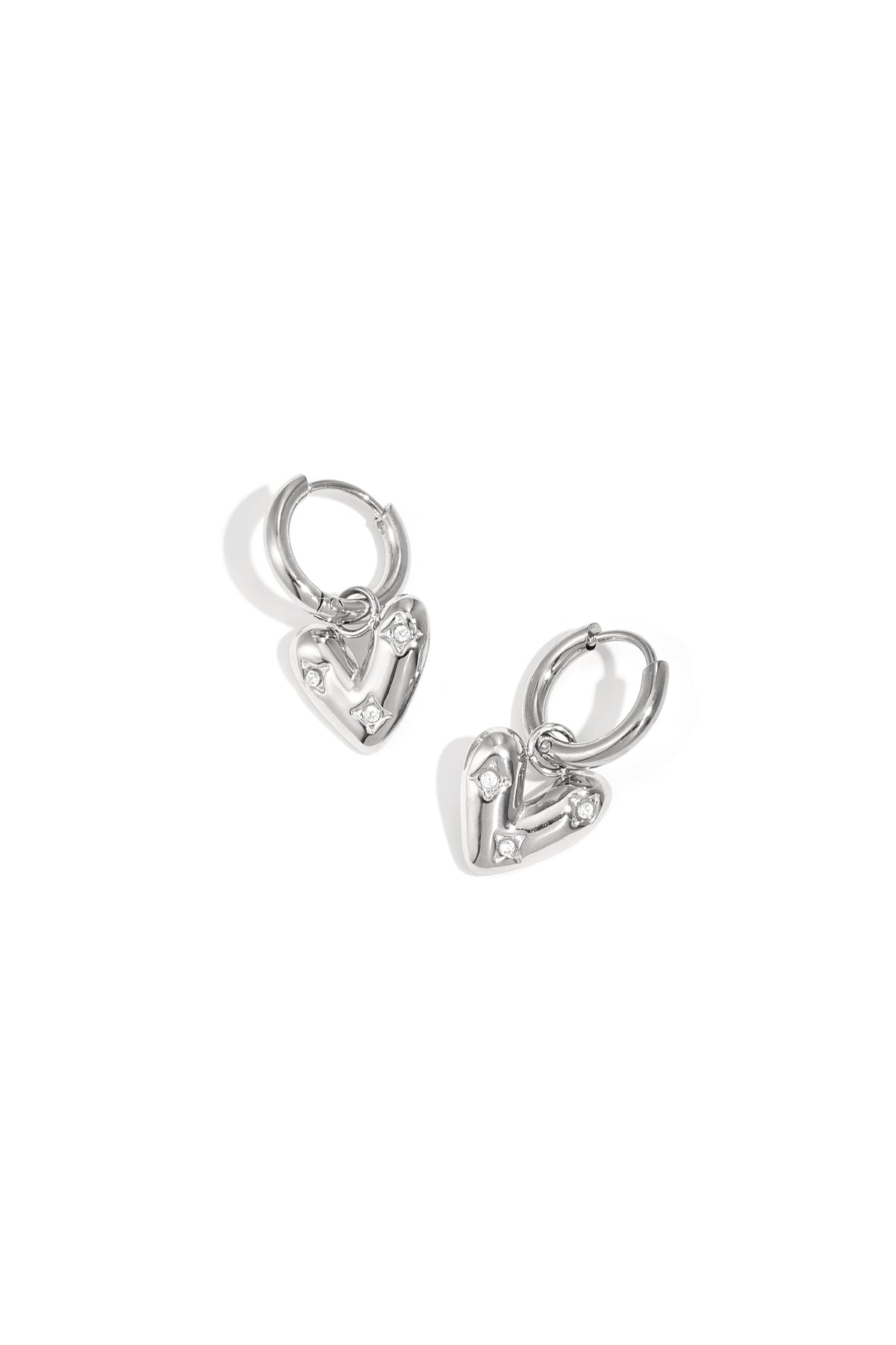Silver heart charm hoop earrings with small zirconia stones on a white background