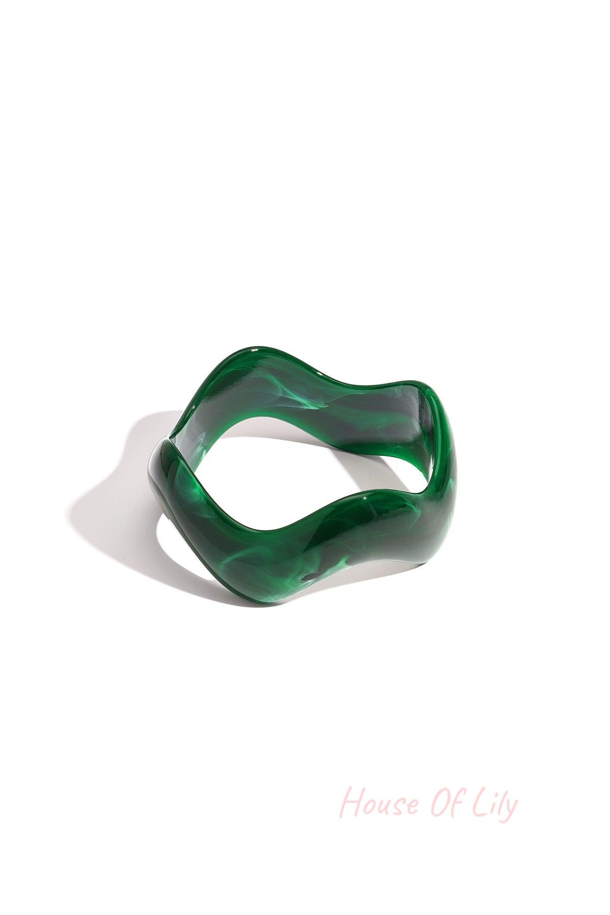 Green acrylic bangle with marbled pattern and irregular wavy design on white background