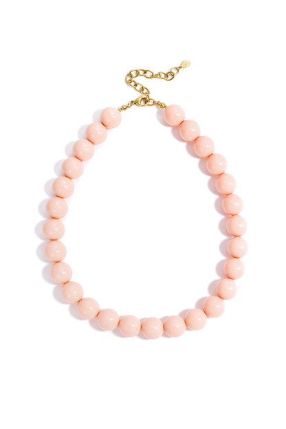 Chunky necklace featuring large, smooth, soft pink beads on a gold-tone chain against a white background.