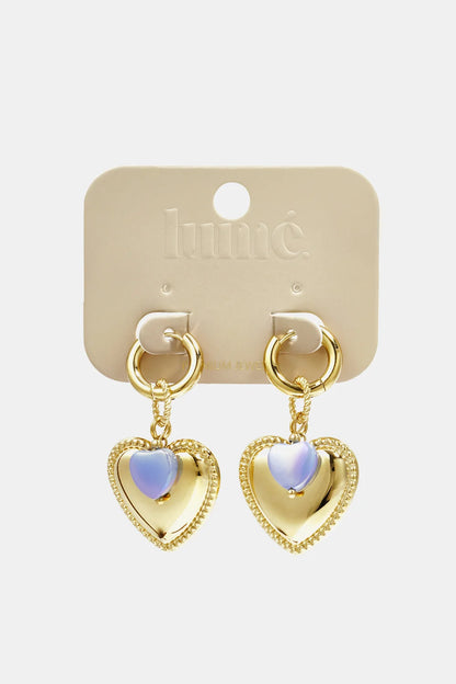 Gold-tone drop hoop earrings featuring polished heart charms with iridescent, lavender-tinted center stone accents.