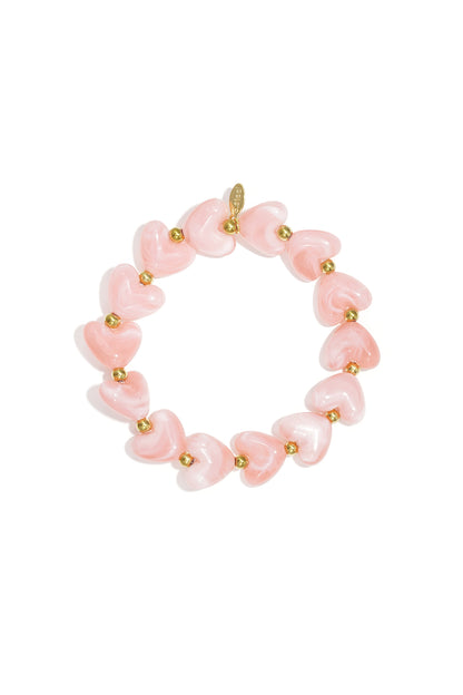 Stretch bracelet featuring pink marbled heart-shaped beads and small gold metal spheres on a white background.