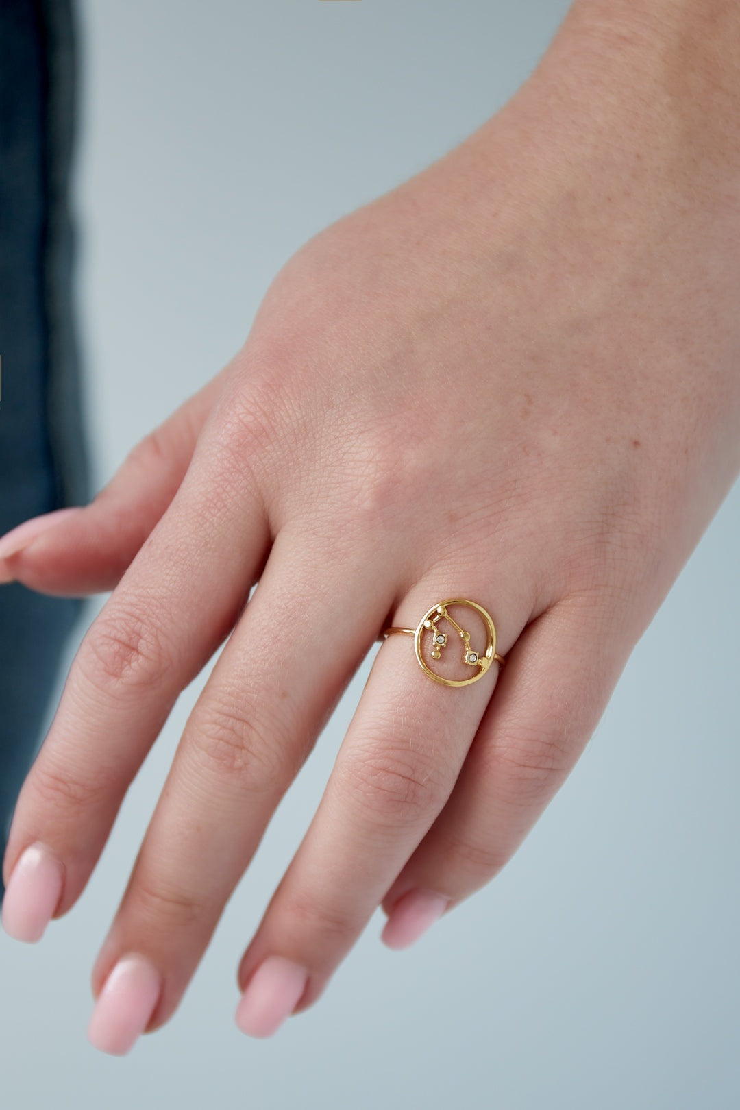 Female hand wearing gold zodiac constellation ring with delicate rhinestone details