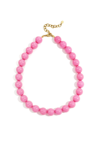 Pink chunky resin beaded necklace with gold chain extension on white background