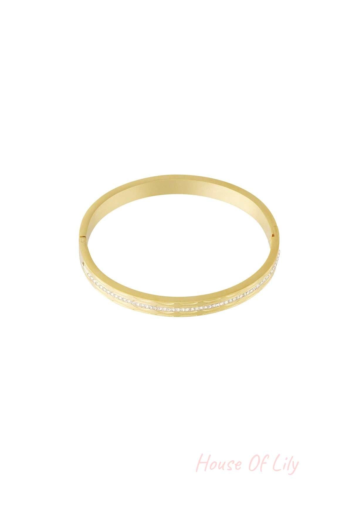 Single gold-tone bangle with a row of small, sparkling crystals in the center, isolated on white background