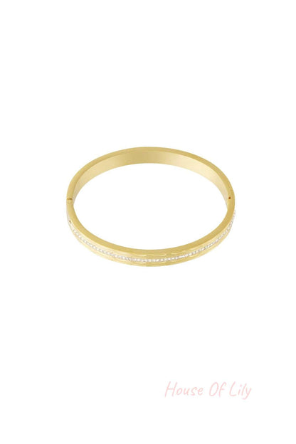 Single gold-tone bangle with a row of small, sparkling crystals in the center, isolated on white background