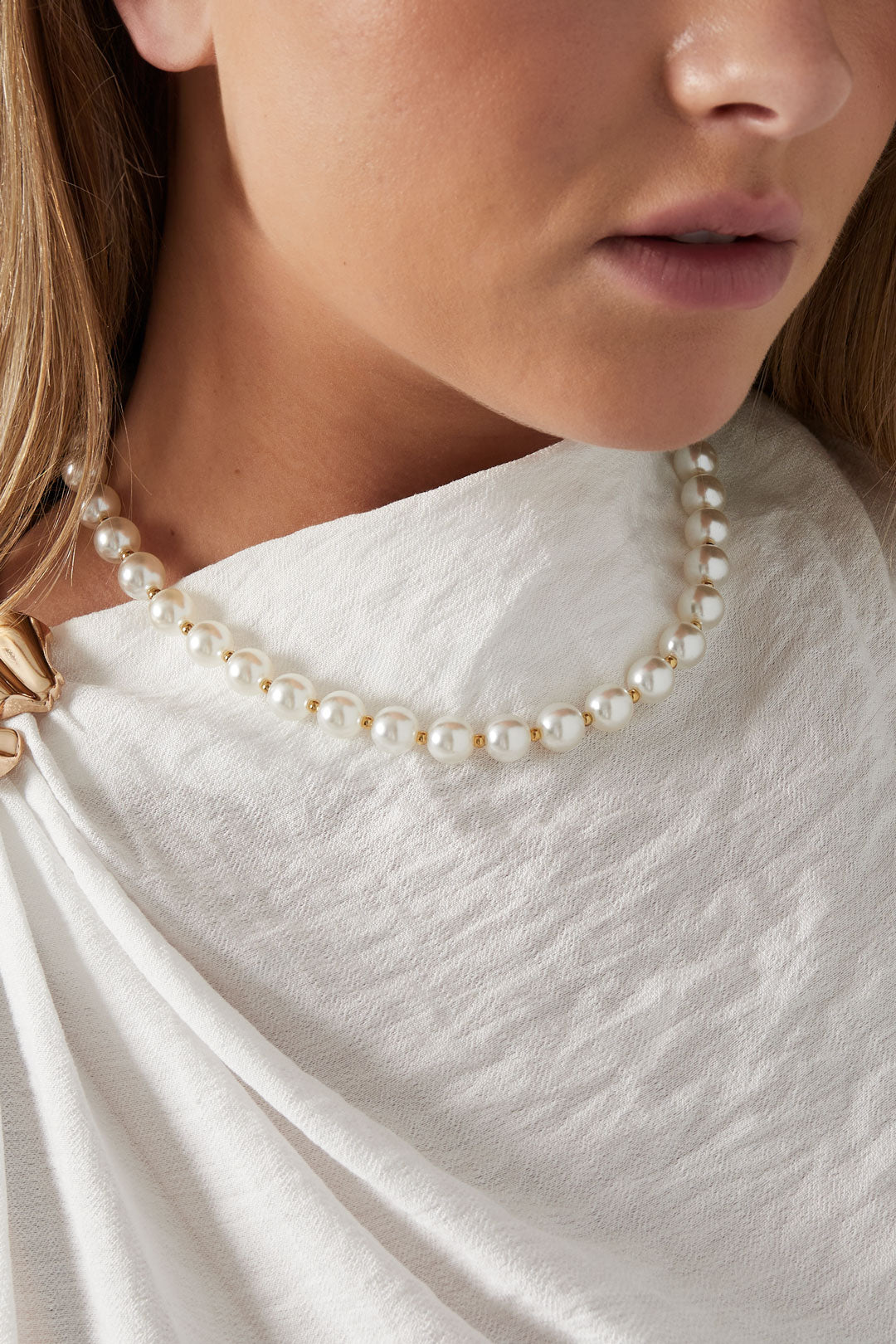 Model wearing pearl white acrylic beaded necklace with gold spacers paired with white textured top