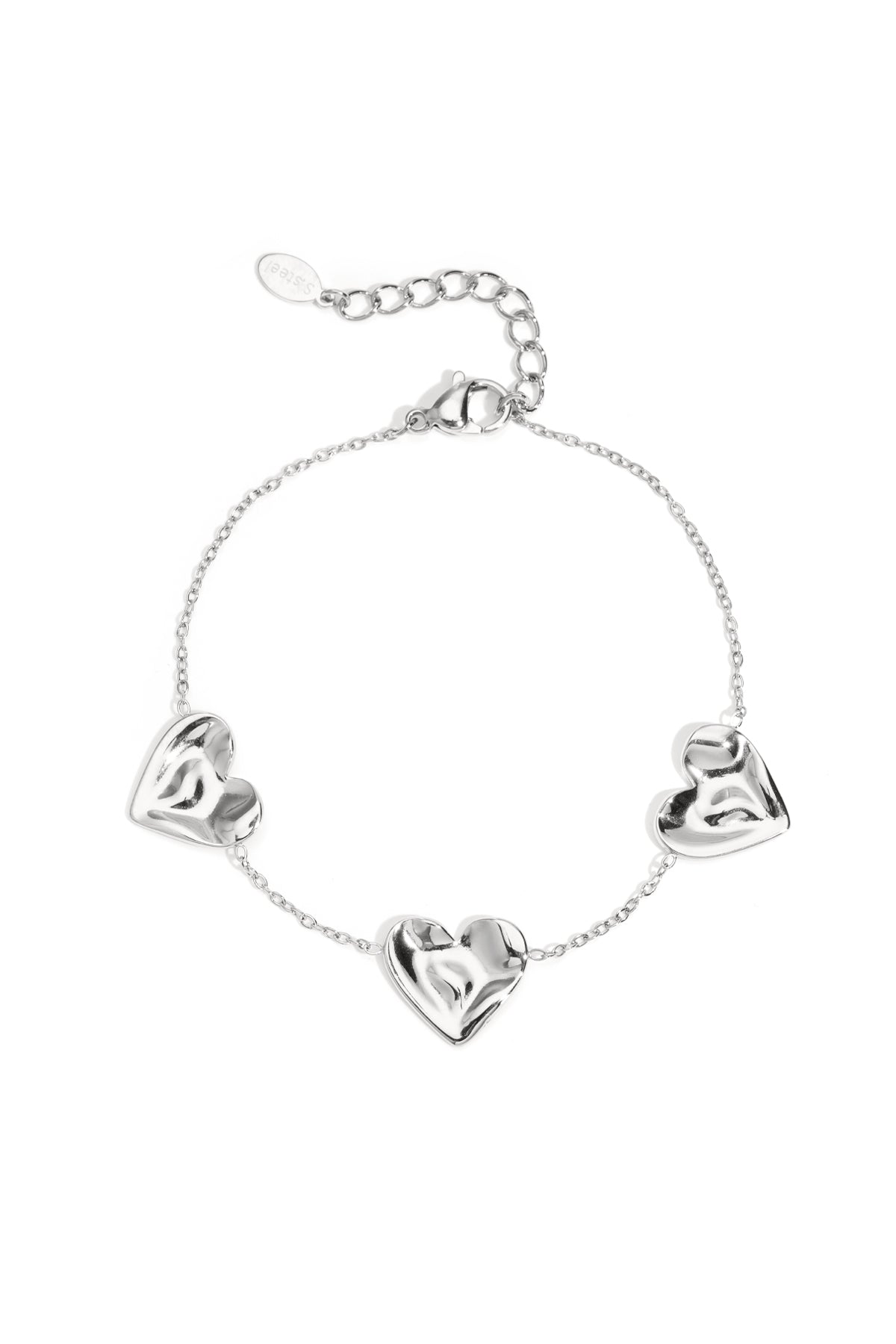 Silver tone charm bracelet with three sculpted heart-shaped charms linked by delicate chain on white background