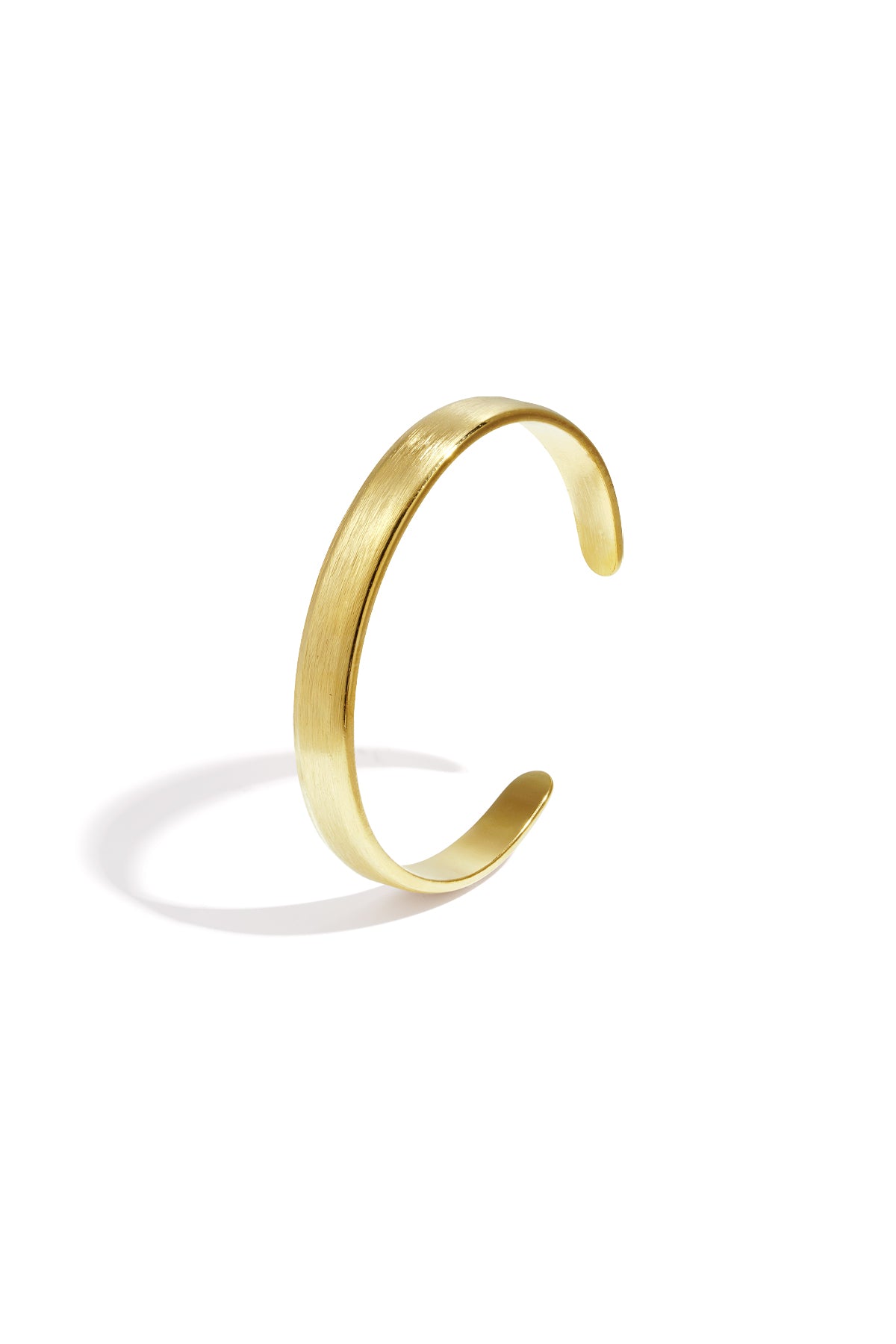 Gold brushed metal cuff bracelet with open curved design on white background
