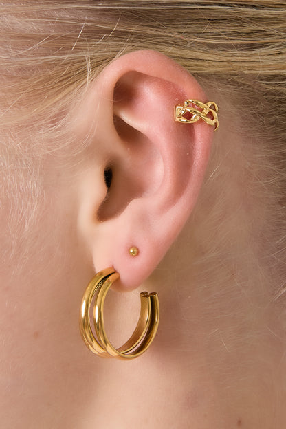 Model wearing a gold twisted chain ear cuff on upper ear and matching gold hoop earrings, showing soft youthful styling
