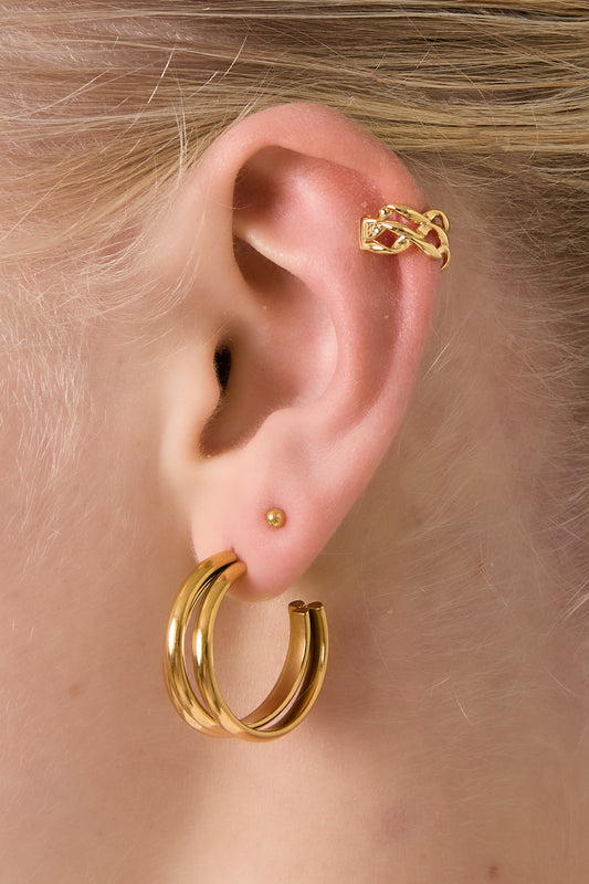 Model wearing a gold twisted chain ear cuff on upper ear and matching gold hoop earrings, showing soft youthful styling