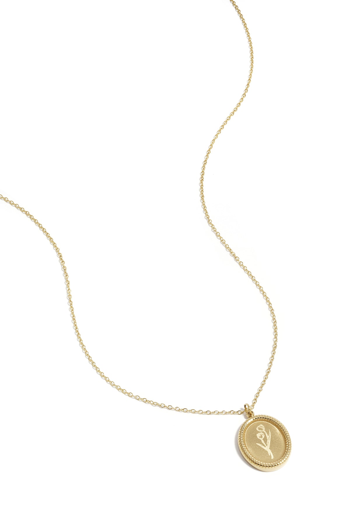 Close-up of gold necklace with tulip blossom pendant on white background