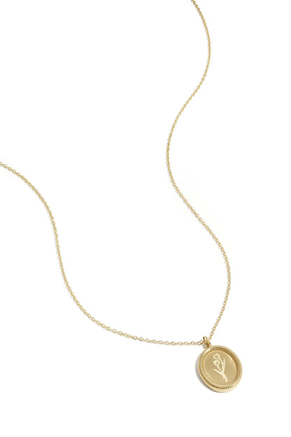 Close-up of gold necklace with tulip blossom pendant on white background