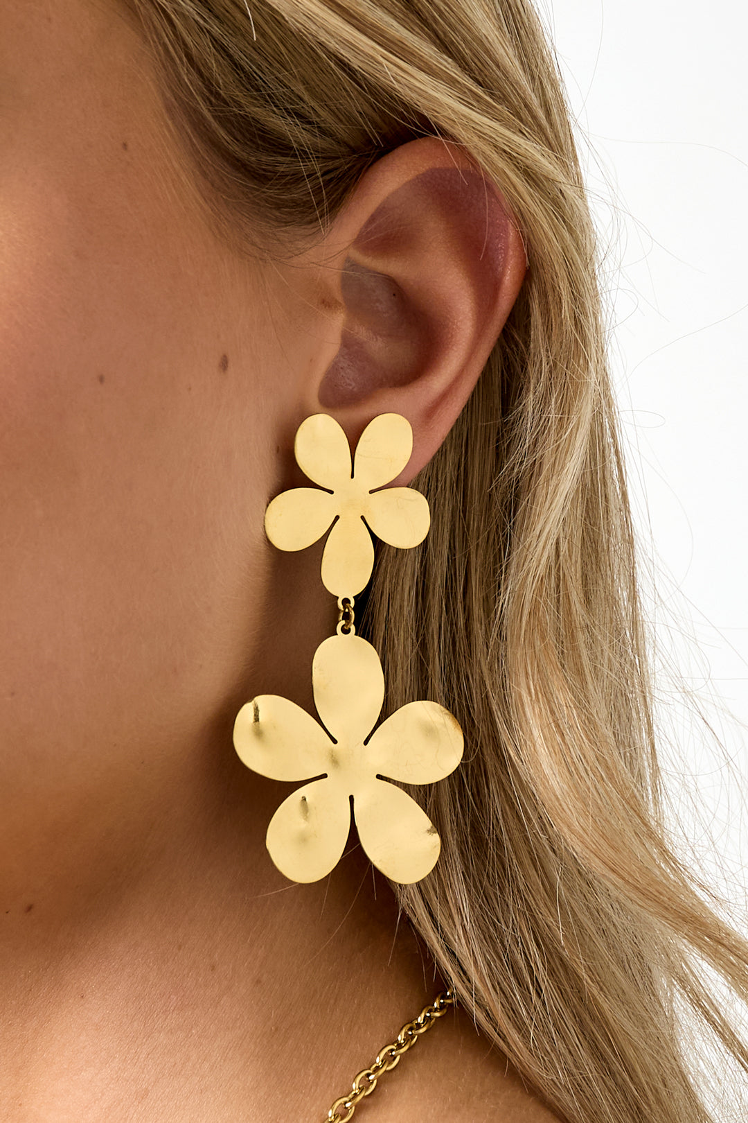 Close-up detailed side view showing floral drop earrings' polished gold flower design on woman's ear