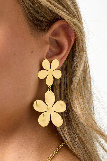 Close-up detailed side view showing floral drop earrings' polished gold flower design on woman's ear