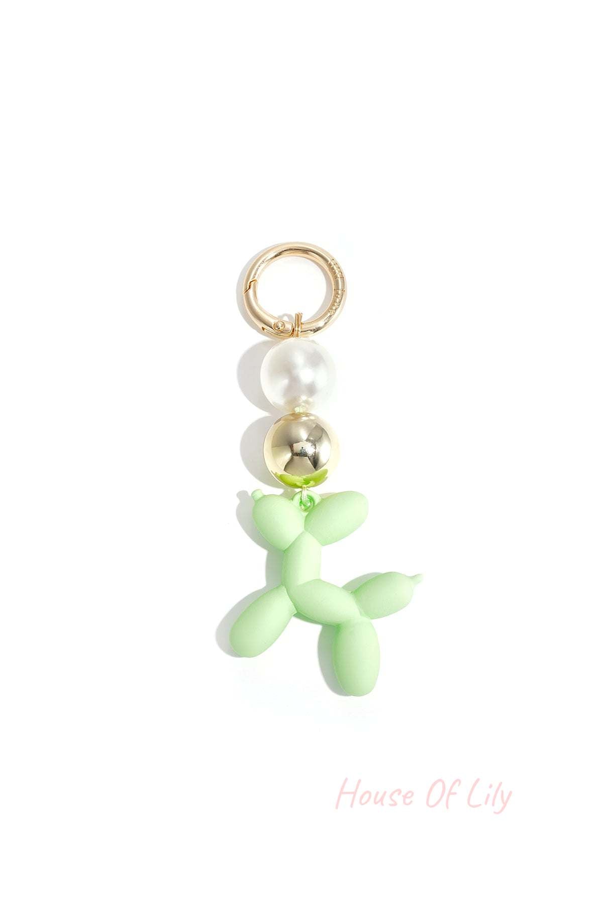 Green balloon dog bag charm featuring pearl and gold beads on white background