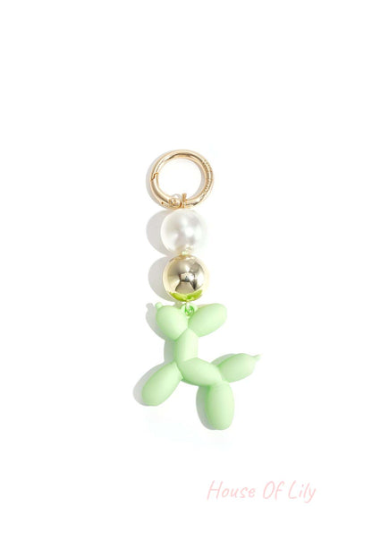 Green balloon dog bag charm featuring pearl and gold beads on white background