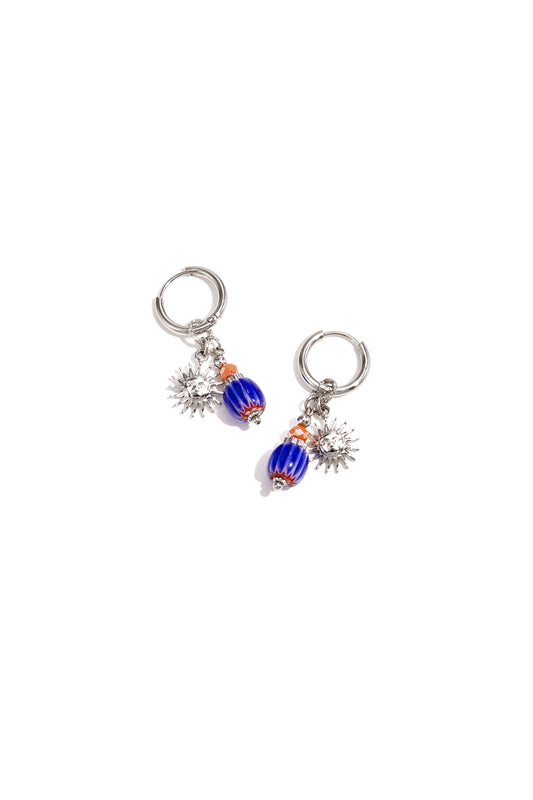 Silver tone hoop earrings featuring sun charms and blue-orange glass beads on white background
