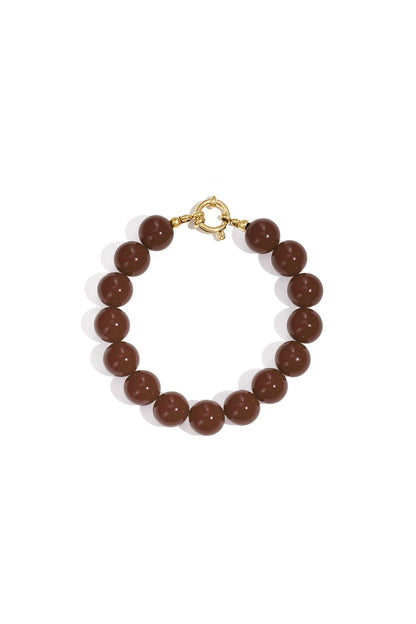 Bracelet of glossy, dark brown spherical resin beads with a gold-tone circular clasp on a white background.