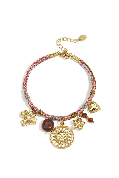 Braided pink and gold-tone charm bracelet featuring sun, flower, heart, and bead charms on white background