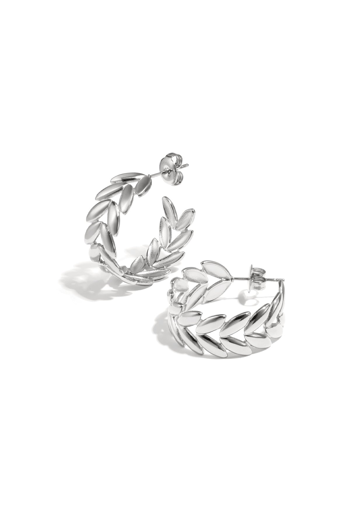 Pair of silver leaf motif hoop earrings with polished finish on white background