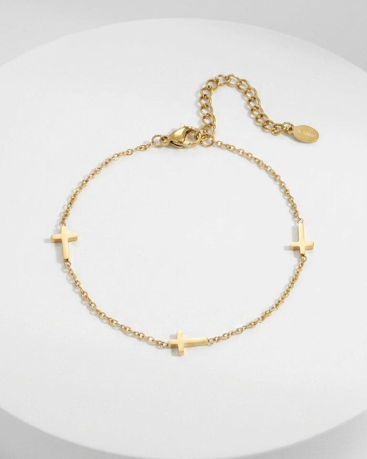Delicate gold-colored metal chain bracelet with three small cross charms evenly spaced along the link.