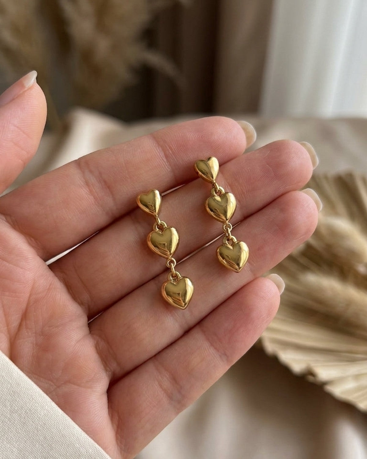 Heart Dangle Earrings: Gold-plated drop earrings featuring three graduated puffed hearts linked in a vertical chain.
