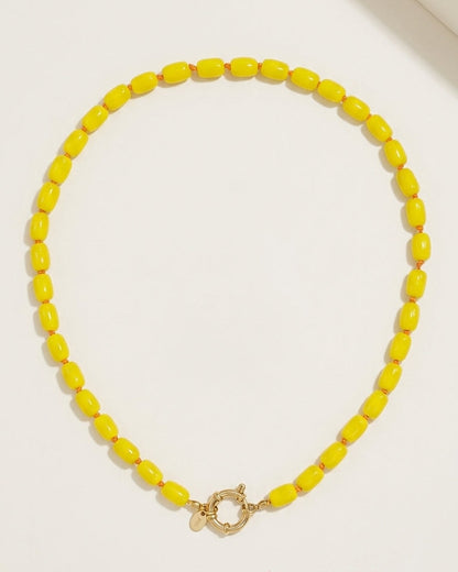 A yellow beaded necklace with cylindrical beads and a gold-colored clasp.