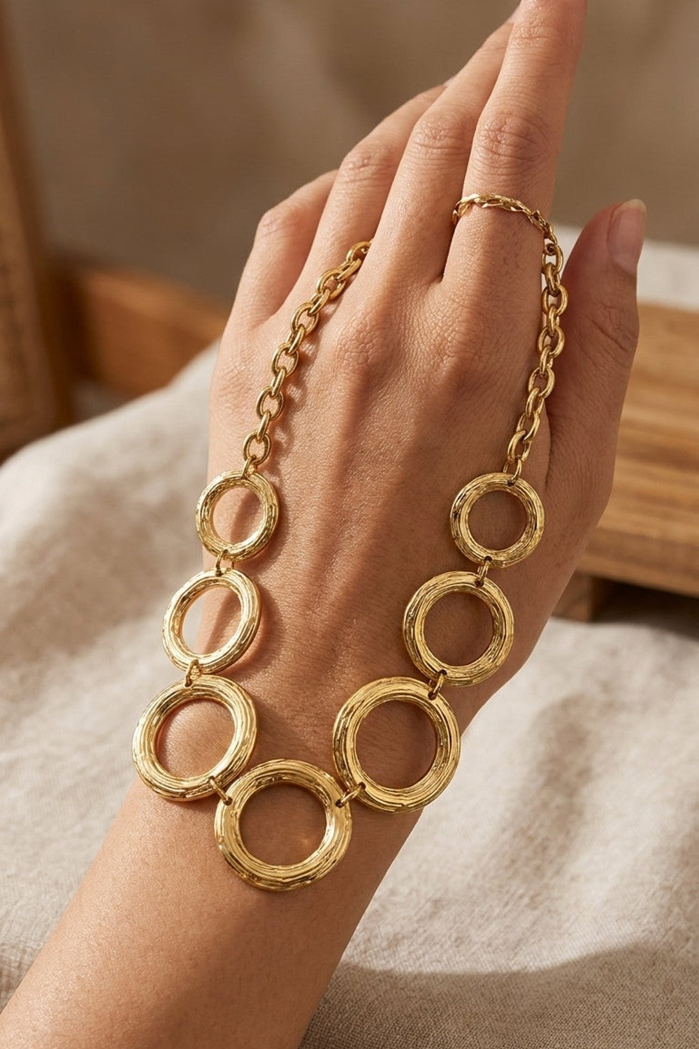 Gilded chain statement necklace featuring interlocking gold rings with a textured finish.