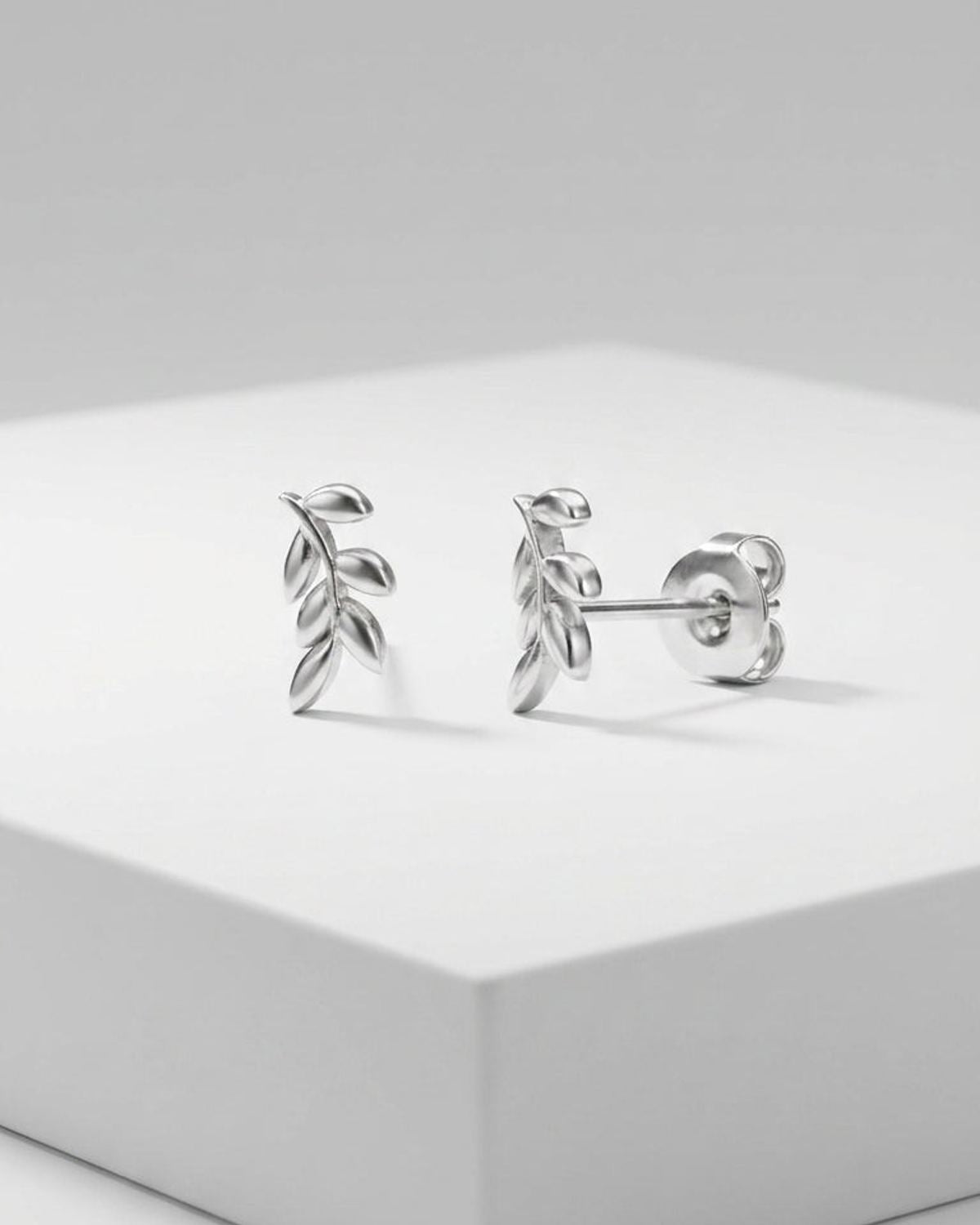 Sprout Vibe Gold stud earrings in polished gold, shaped like delicate leaf sprigs with secure backings on white.