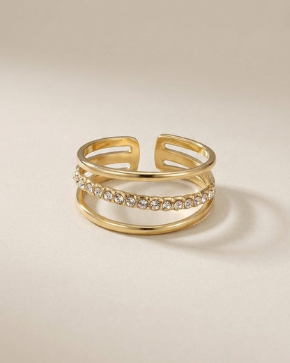 Gold-colored triple-band ring with a row of clear round stones inset on the middle band.