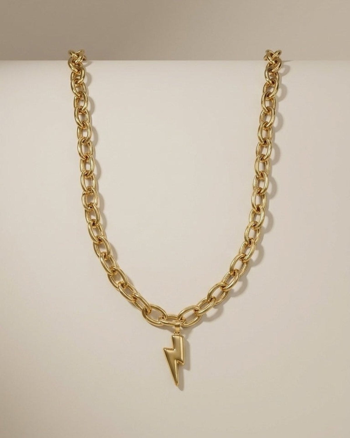 Gold chain necklace with a chunky lightning bolt pendant displayed against a neutral background.