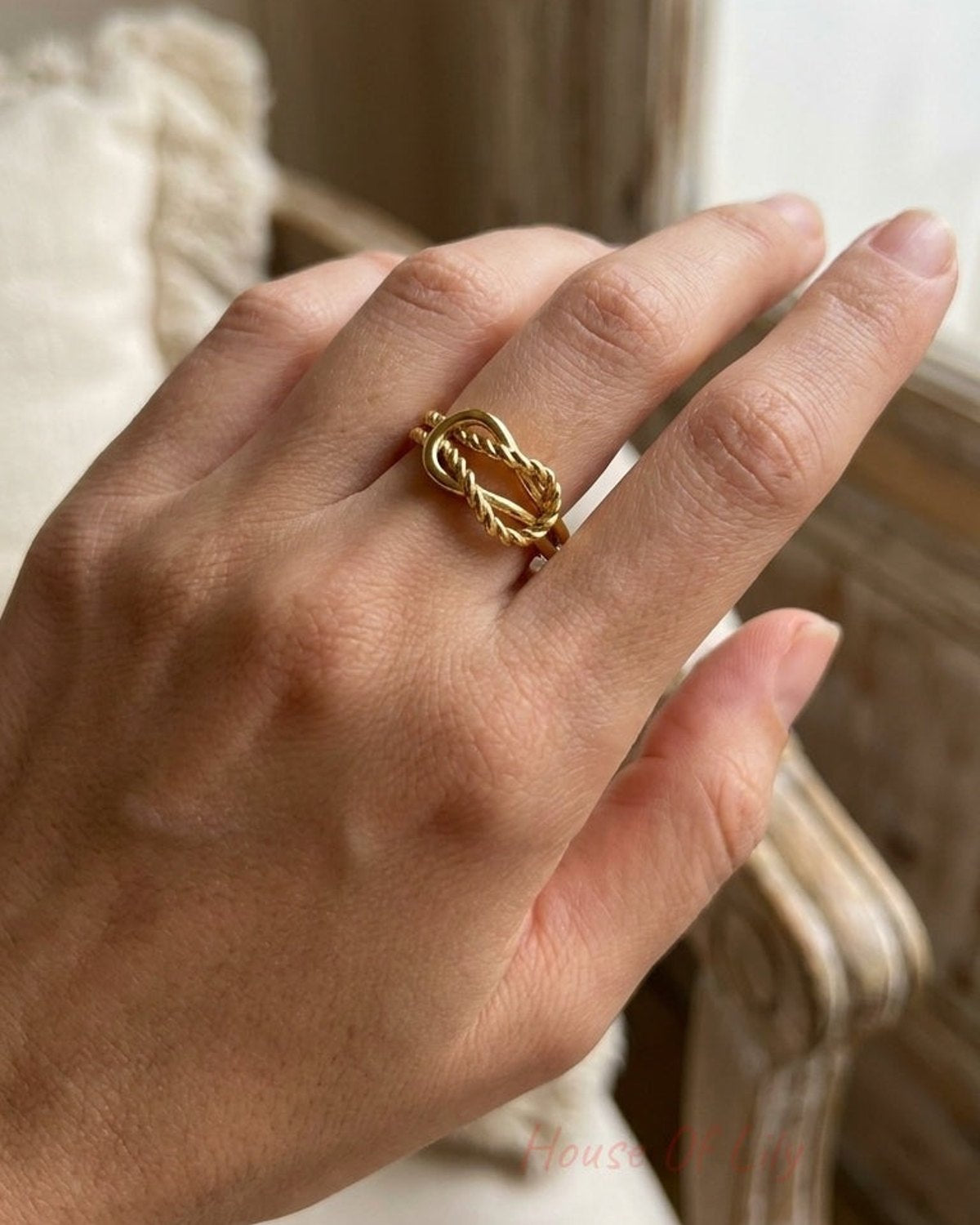 A gold twisted metal statement ring worn on a woman's finger.