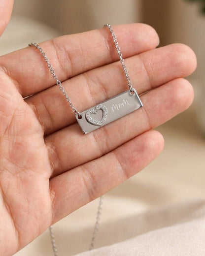 Silver chain necklace with a bar pendant engraved with "mom" and a crystal-paved heart.