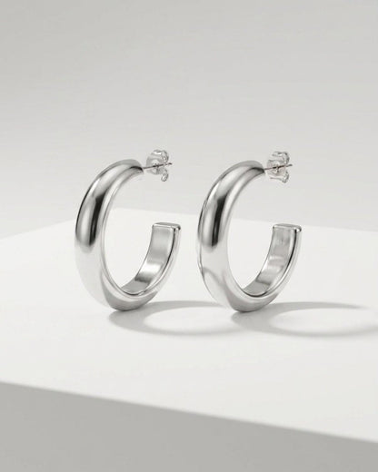 Chunky silver hoop earrings with a polished, minimalist finish on a white surface.