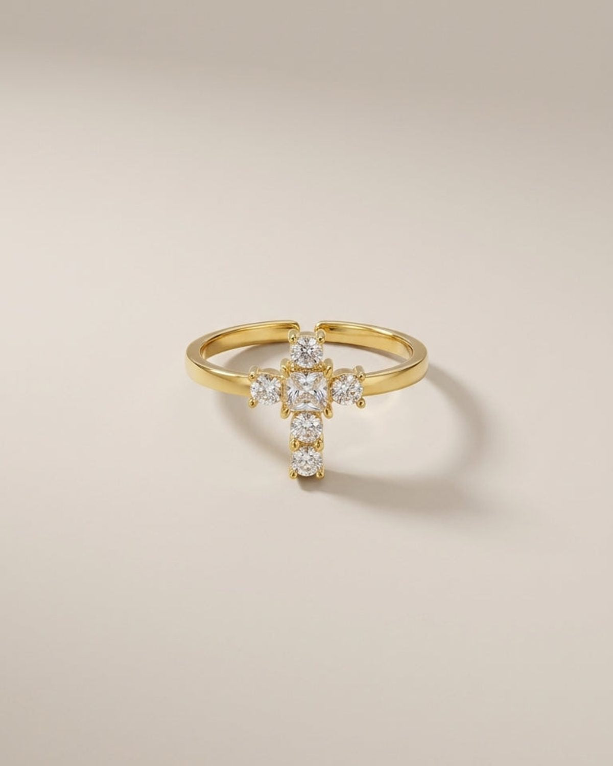 Gold ring with a cross-shaped setting featuring clear cubic zirconia stones.