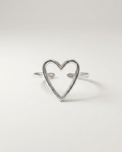 Silver-colored minimalist ring featuring an open-faced heart outline against a plain light gray background.
