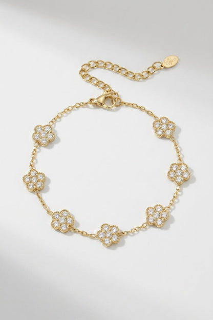 Gold chain bracelet featuring spaced, pavé-set crystal flower charms and an adjustable clasp.