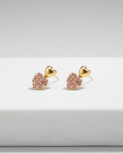 Gold heart stud earrings, each featuring a polished gold heart above a heart paved with pink crystals.