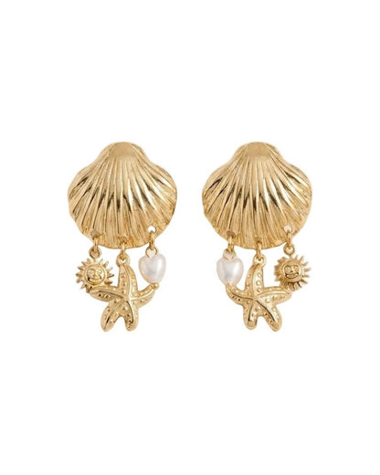 A pair of gold-toned shell-shaped earrings with dangling starfish, sun, and pearl charms, displayed on a light beige background.