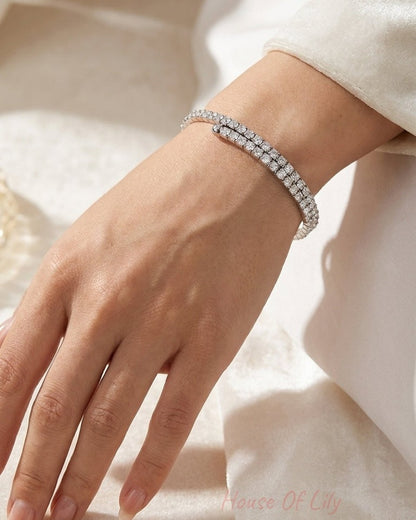 A silver wrap-around tennis bracelet with a continuous row of sparkling round-cut diamonds on a woman's wrist.