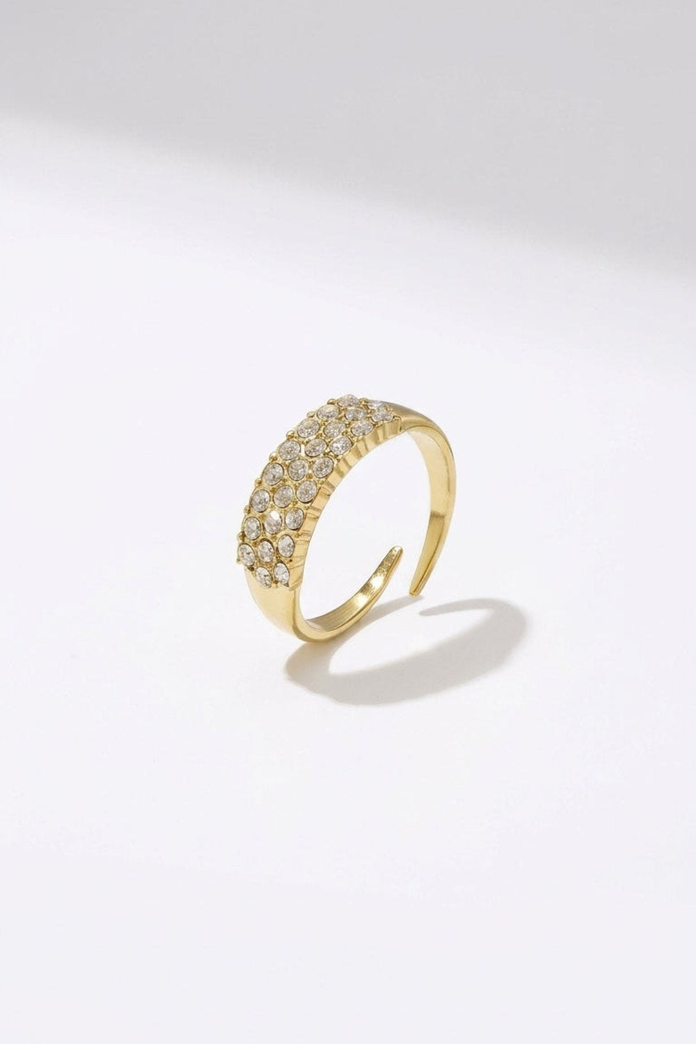 Gold-colored open ring pavé-set with multiple tiny clear rhinestones along the top band.