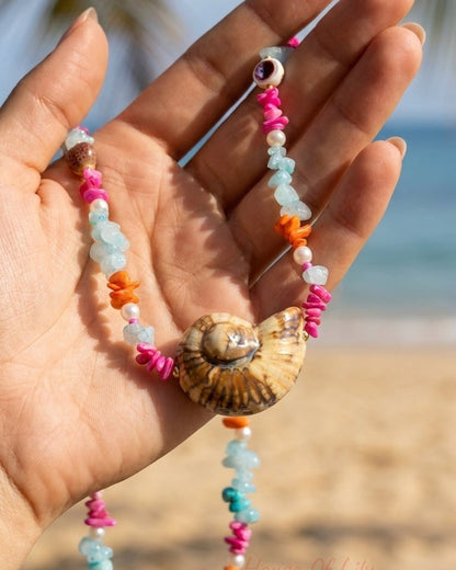 Tropical shell necklace with pink, blue, orange, and white stone chip beads, centered on a spiral sea snail shell.