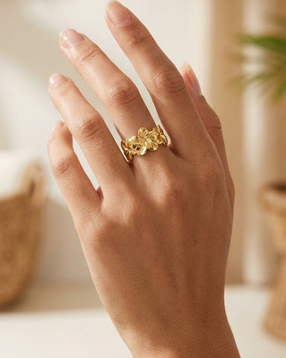 Hibiscus Bloom Ring in polished gold, featuring a band of sculpted floral shapes worn on a finger.