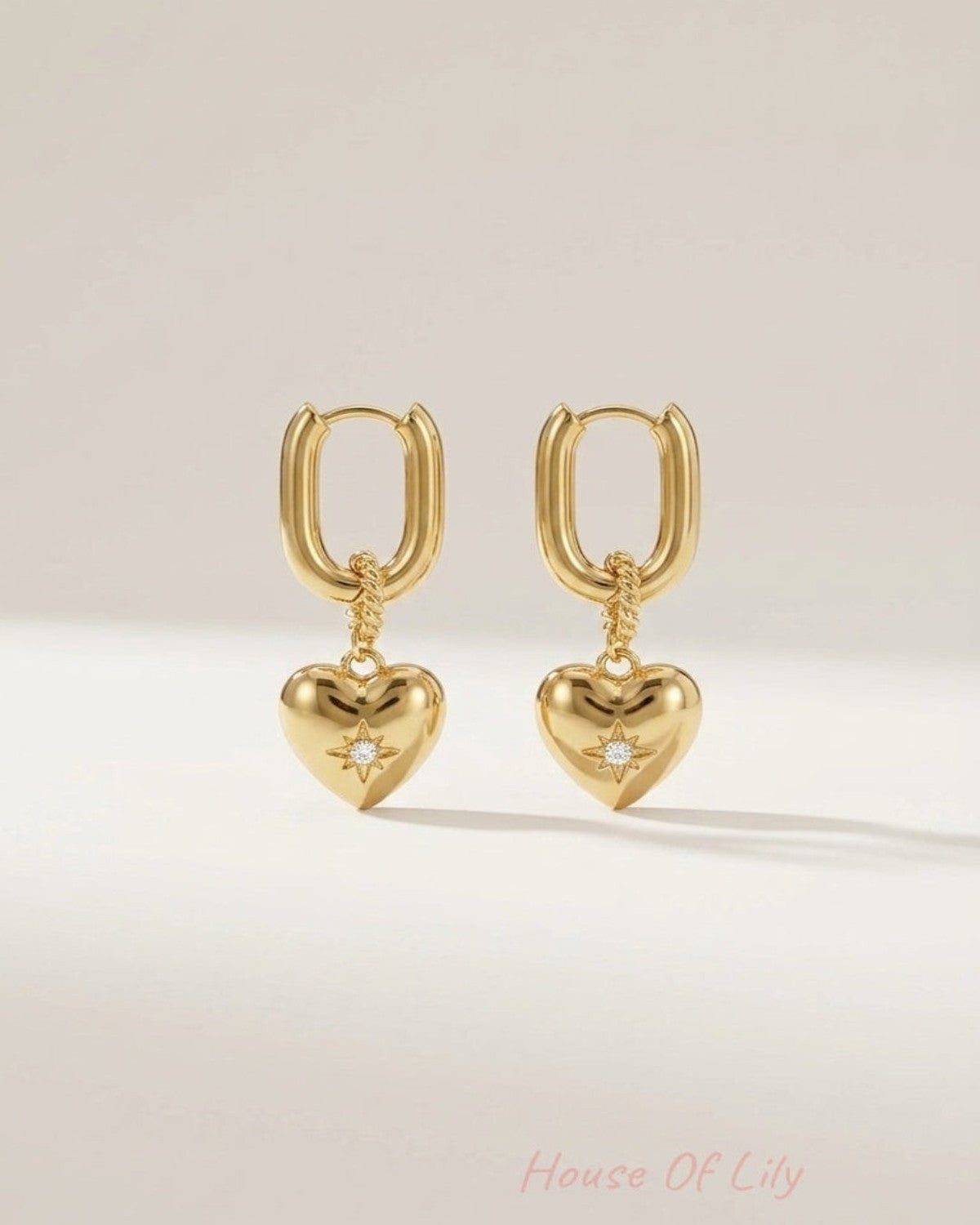 Gold drop earrings featuring a thick rectangular hoop, twisted connector, and puffy heart pendant with a flush-set zircon star.