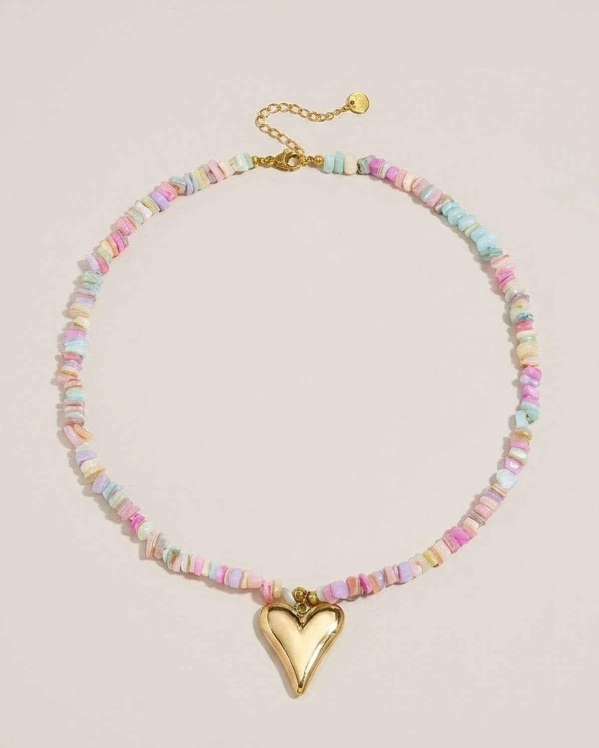 A necklace of multicolored pastel chip beads featuring a polished gold heart pendant.